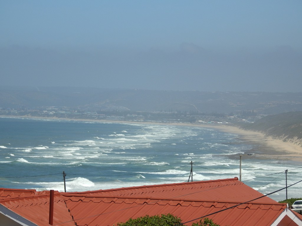 View over red rooftops to the waves and beach of the bay from Julsie's Home