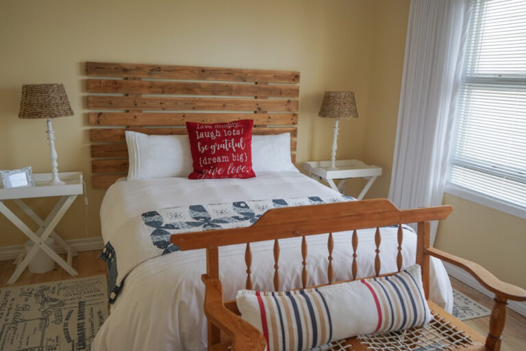 Room 2 queen bed with wooden headboard and striped day bench